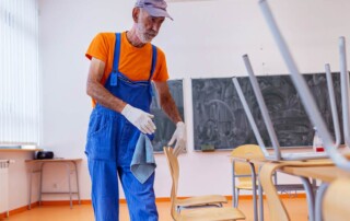 Custodian cleaning schools by disinfecting classroom surfaces