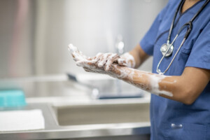 A healthcare worker performing hand hygiene in a hospital room, illustrating infection prevention.